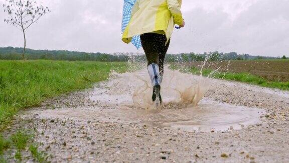 小女孩跑过泥泞的水坑