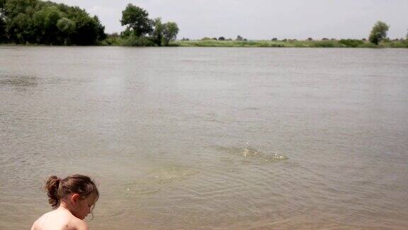一个小女孩往河岸上的水里扔石头慢动作