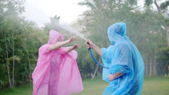 亚洲夫妇穿着五颜六色的雨衣面带微笑在雨中嬉戏