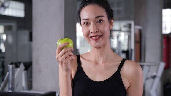 亚洲美女在健身房咬青苹果的肖像