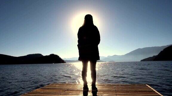 一个女人走在木码头上的湖边