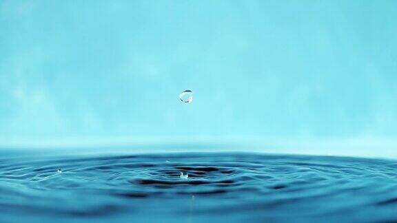 慢动作4k视频水面与下落的水滴在蓝色背景泼水工作室拍摄