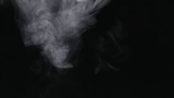 在黑色背景上吹着白色烟雾的水平蒸汽以慢动作上升