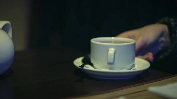一位女士从自助餐厅的桌子上拿出一杯茶