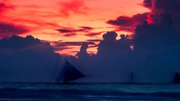 日落时云朵背景上的帆船剪影