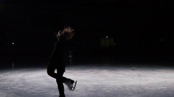溜冰者在一个美丽的轮廓光加速和停止黑色套装从冰鞋上飞出的冰碎片进行了一个三圈跳跃绕轴旋转下降失败糟糕的尝试掉在冰上