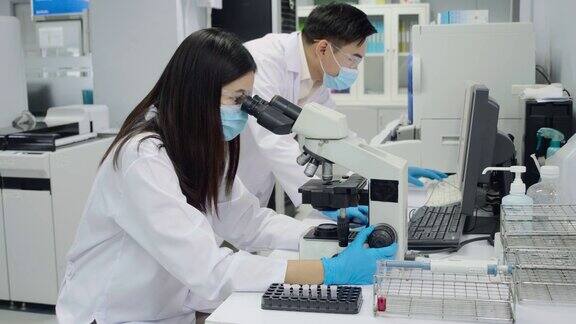 科学家正在看显微镜男女医生在讨论一种用电脑设备进行的血液测试
