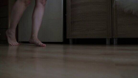 一个美丽的女孩光着脚在房间的地板上走着