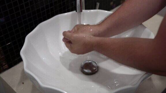 特写男子在水龙头下用肥皂洗手浴室里有水