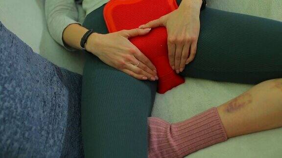 女孩把一个温暖的加热垫放在肚子上以缓解经前症候群的症状