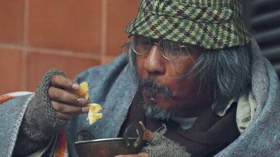 4K一个无家可归的老人在城市的人行道上吃东西