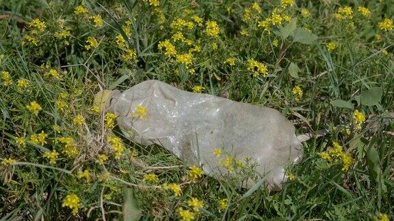 废弃塑料瓶的特写在美丽的草地鲜花塑料垃圾环境污染问题4k-60fps