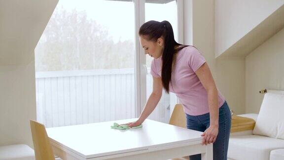 妇女在家里用超细纤维布擦桌子