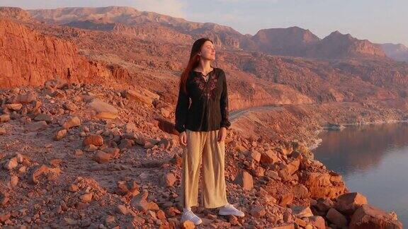 快乐的女性旅行者凝视着约旦死海上的日落美景