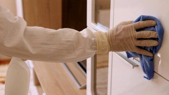 一个穿着防护服和手套的男人在公寓里消毒表面