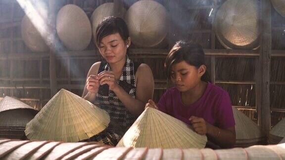两名同胞越南工匠在老传统房子制作传统越南帽子的4k镜头低光场景在ApThoiPhuoc村Cantho省越南传统艺术家
