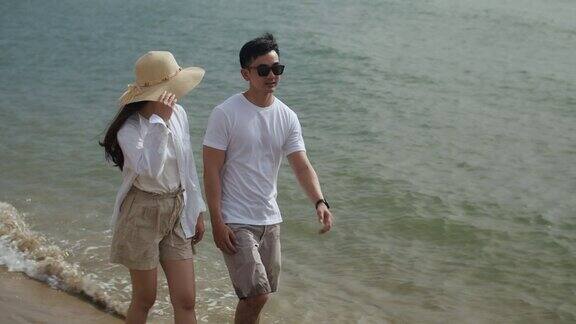 快乐的亚洲情侣在海边散步享受假期的夏天愉快地谈笑看着海滩上的风景
