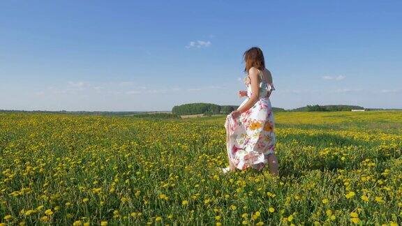 快乐的女人走在盛开的黄色田野上穿着随风飘动的裙子