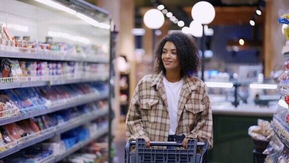 微笑的非洲裔美国妇女走过超市购物车