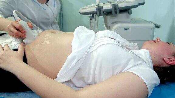 女医生在门诊对孕妇腹部做超声检查