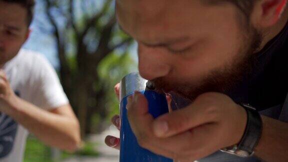 口渴的男游客在公园的饮水机里喝水