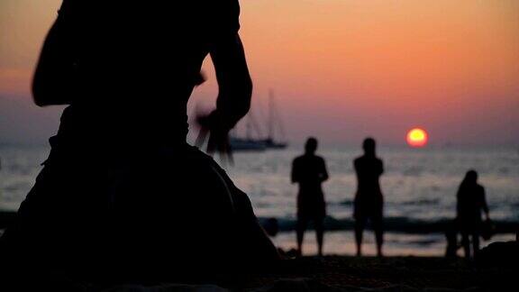日落时分一个男人在海滩上敲手鼓