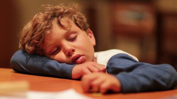 累了的孩子趴在桌子上睡着了小男孩在漫长的一天之后睡着了真实的生活真实的自然睡眠孩子的照片