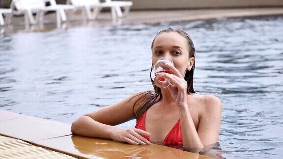 穿着红色比基尼的漂亮女人在暑假的游泳池里放松