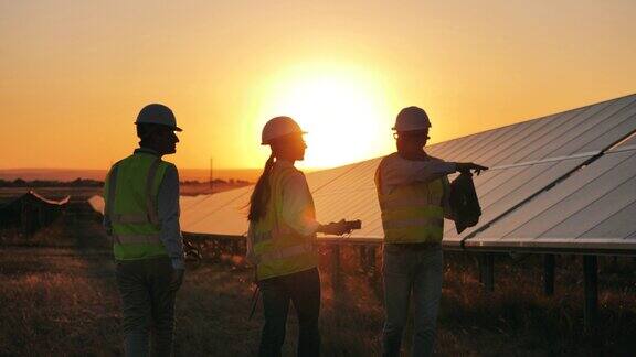 几名太阳能专家在日落时监测太阳能发电厂替代绿色能源工作者