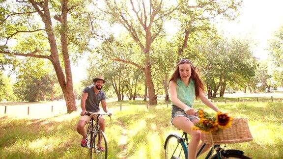 一对快乐的情侣在公园里一起骑车