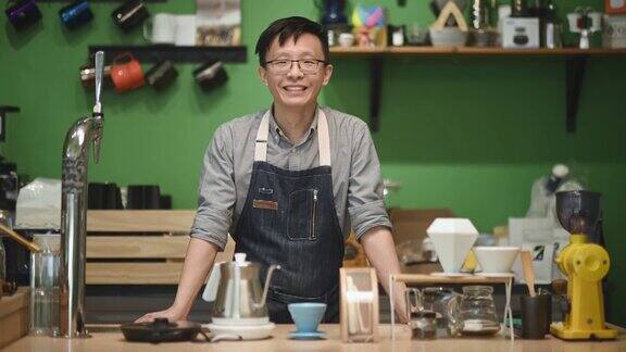 亚洲华人咖啡师在咖啡厅柜台微笑看着镜头