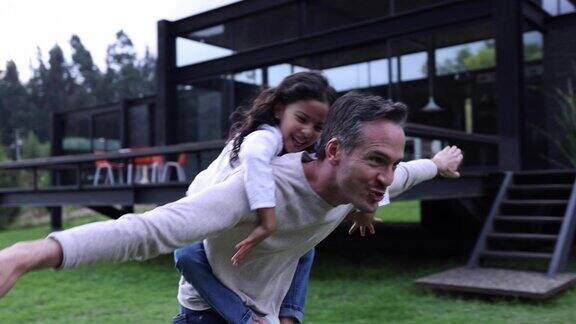 快乐的拉丁美洲父亲有乐趣玩飞机与他的女儿都微笑着