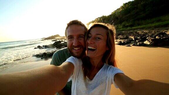 一对快乐的年轻夫妇在海滩上拍自拍照