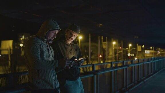 SLOMO两个歹徒晚上在城市里用智能手机