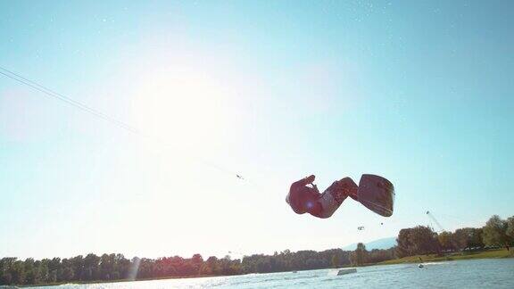 慢动作:运动男子水上滑板做一个后空翻跨越蓝色的天空