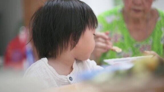 亚洲华人祖母在家里喂可爱的男婴