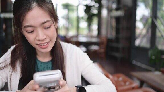 年轻的z一代亚洲女性拿着相机和她的朋友在咖啡馆里合影心情愉快