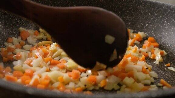 慢动作在煎锅中翻炒洋葱、胡萝卜、大蒜