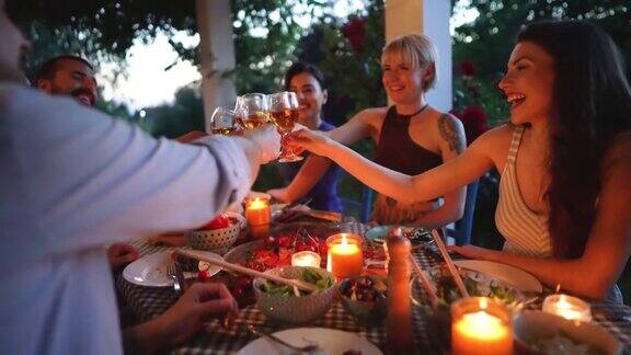 一群快乐的朋友在晚宴上用白葡萄酒敬酒