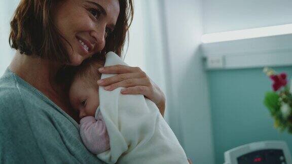 体贴的年轻母亲微笑着拥抱着婴儿