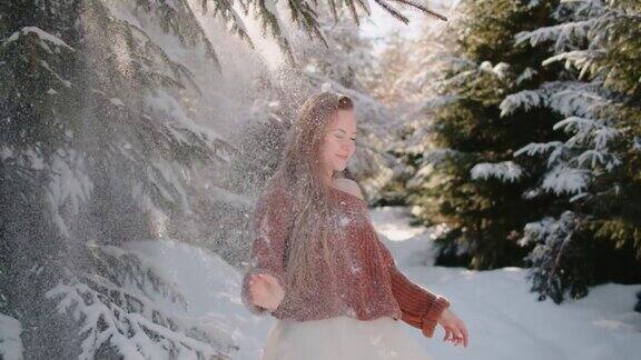 穿着针织毛衣婚纱的新娘在森林里的雪花下笑着旋转