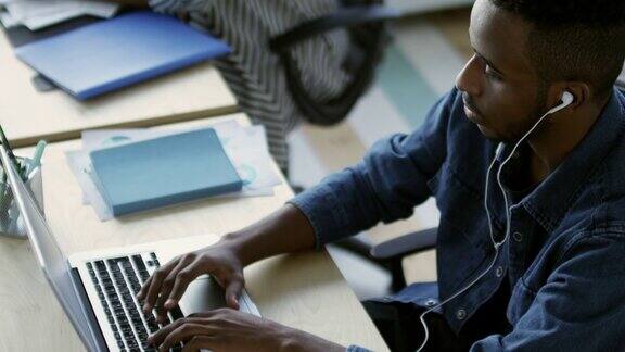非洲办公室职员戴着耳机使用笔记本电脑