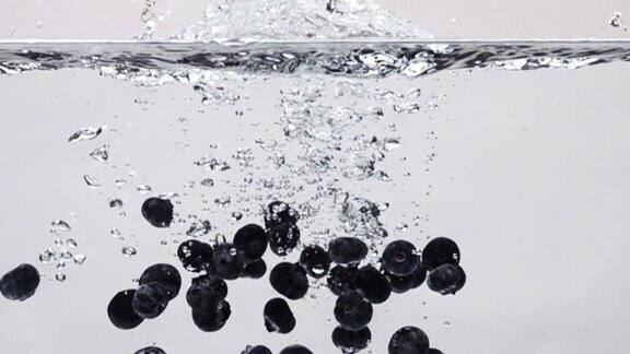 超级慢动作:蓝莓滴入淡水在白色的背景
