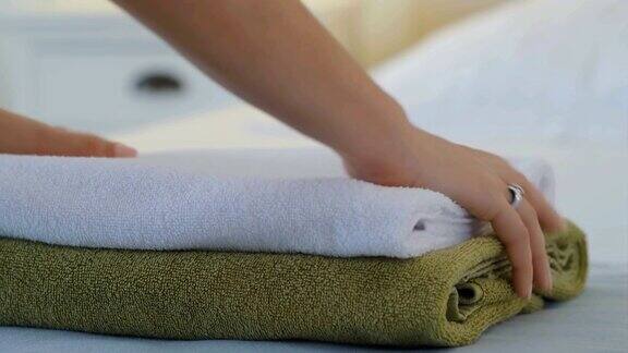 一个女人把干净的毛巾放在床上然后用手把它摸平