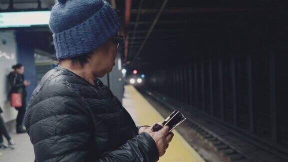 女游客在地铁站台上用手机等待和发短信