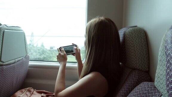 在高铁上女性用手机拍摄外部景色