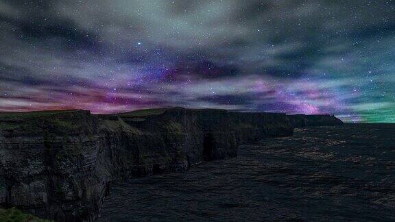 在美丽的银河映衬下夜晚的天空随着云朵在爱尔兰的莫赫悬崖上移动