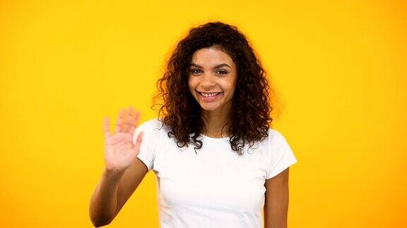 友好的非裔美国女孩挥手向镜头问好欢迎