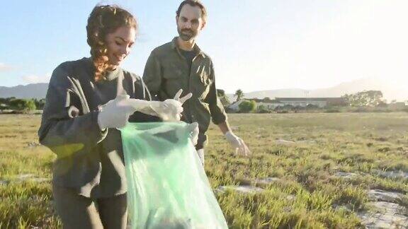 两个微笑的志愿者在田野里捡拾垃圾