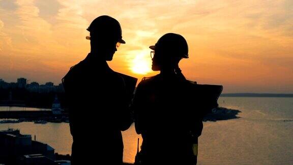 工人们聊天站在夕阳的背景下看背影